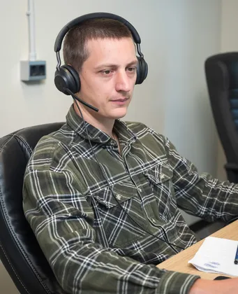 Man wearing a headset with microphone working at a desk during a video call